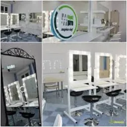 Sala szkoleniowa z lustrami do makijażu z oświetleniem LED, krzesła barowe, stanowiska pracy z kosmetykami, logo firmy na ścianie.