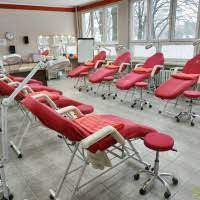 Sala z czerwonymi fotelami do poboru krwi lub wykonywania zabiegów medycznych, widoczne okna i tablica flipchart.