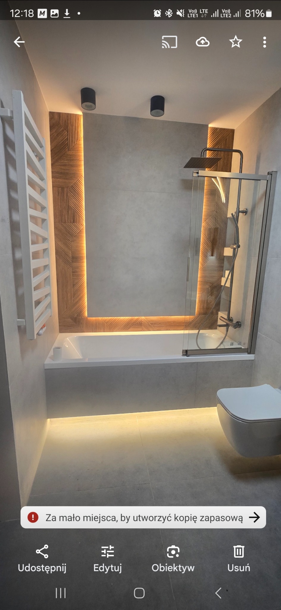 Nowoczesna łazienka z podświetleniem LED: wanna z parawanem, WC, grzejnik drabinkowy. Drewnopodobna mozaika z oświetleniem akcentującym. Minimalistyczny design.