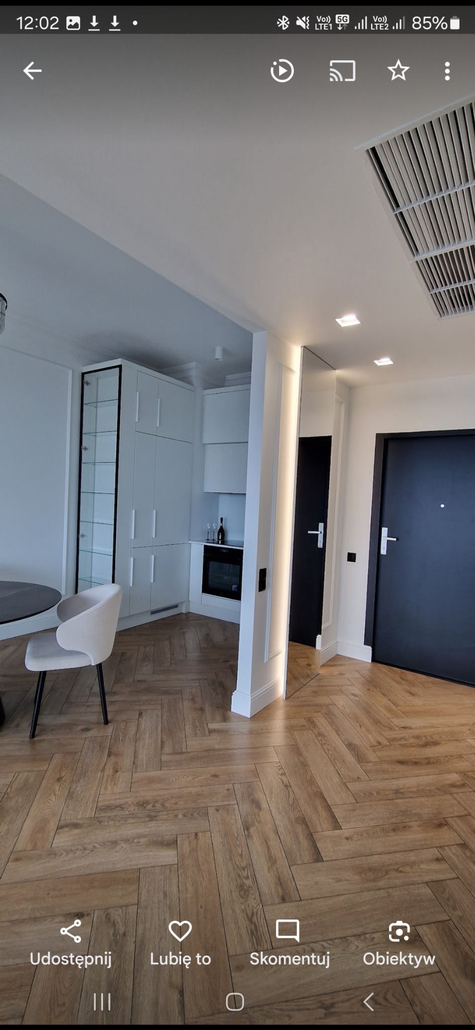 Eleganckie wnętrze po remoncie: parkiet w jodełkę, zabudowa kuchenna w bieli, czarne drzwi i oświetlenie LED. Nowoczesny design.