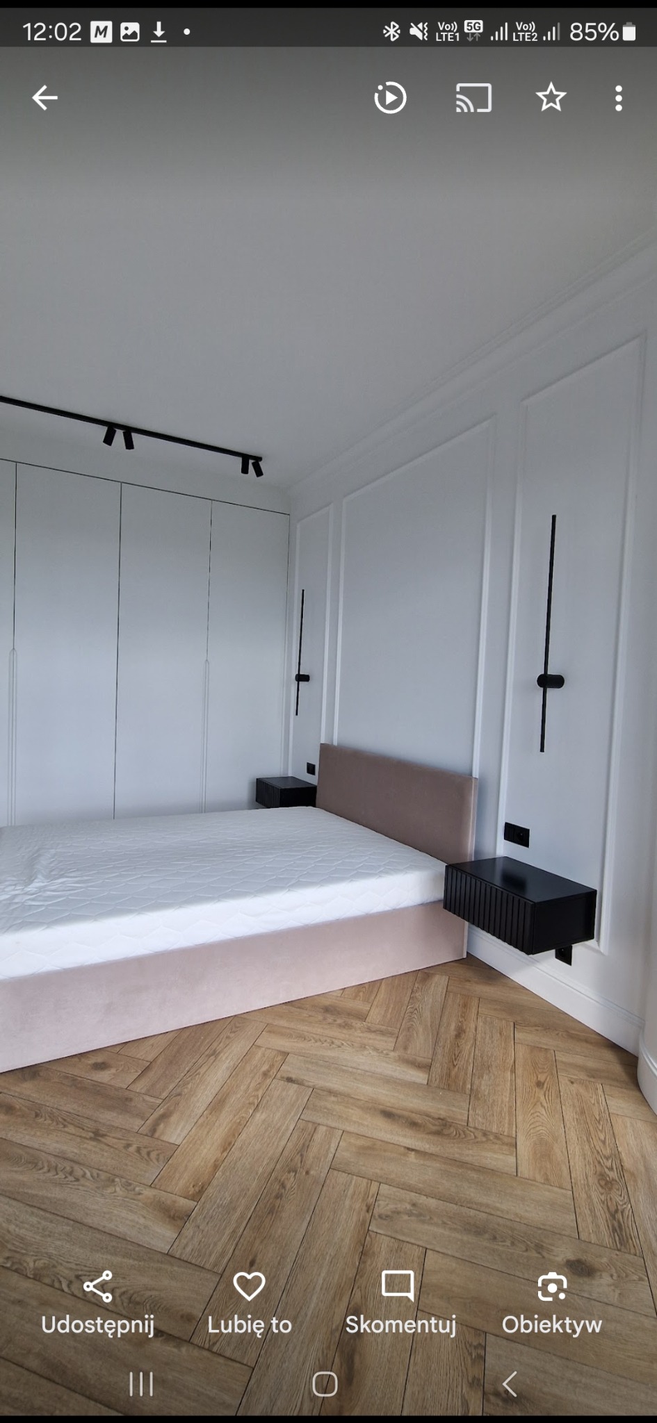 Elegancka sypialnia w bieli i beżu: parkiet w jodełkę, łóżko z tapicerowanym wezgłowiem, minimalistyczne lampy ścienne i szafki nocne. Nowoczesny design wnętrza.