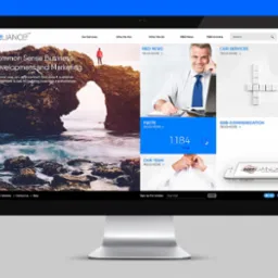 Ekran komputera wyświetla stronę internetową z motywem biznesowym, prezentującą nagłówek z logo firmy, sekcję z malowniczym krajobrazem skalnym i osobą na szczycie, obok sekcji z wizerunkiem...