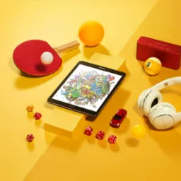 Żółte tło ze starannie rozmieszczonymi przedmiotami: tablet z kolorową grafiką, słuchawki, głośnik, piłeczka bilardowa z numerem 9, rakietka do tenisa stołowego, piłeczki, kostki do gry i model...