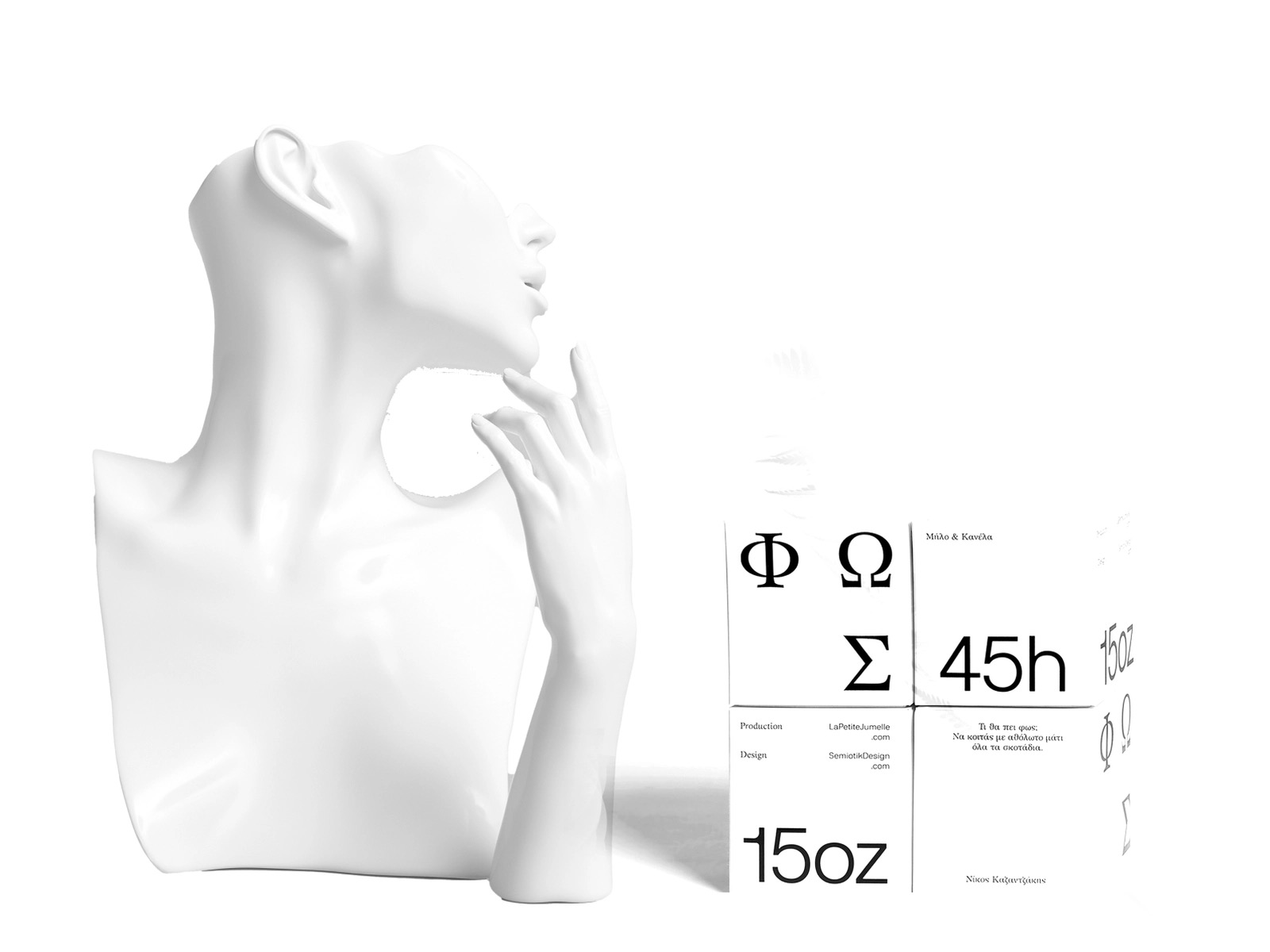 Biały manekin popiersia kobiety z ręką przy twarzy, obok pudełko z greckimi literami i tekstem o produkcji i projekcie.