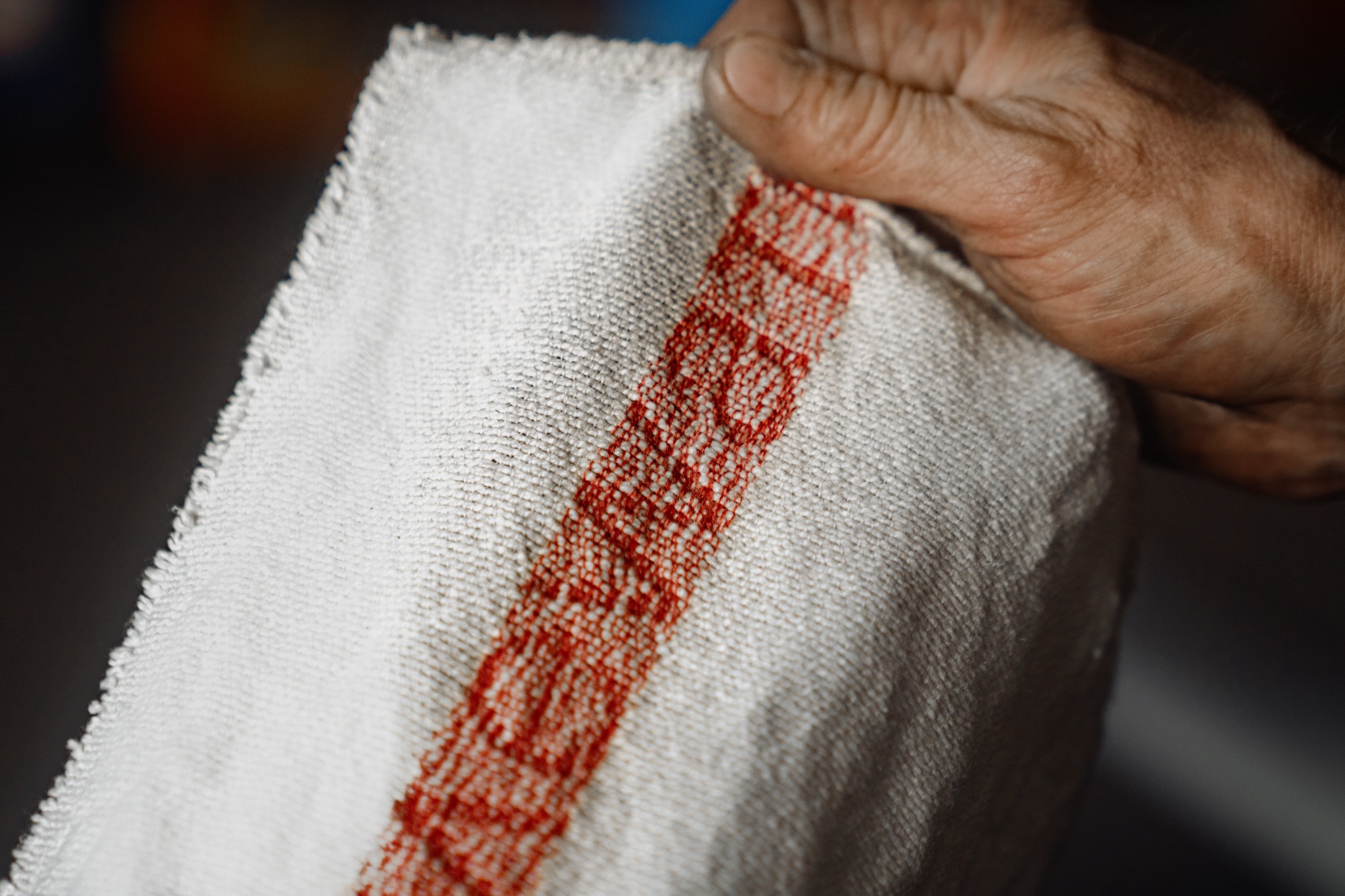 Szmatka warsztatowa z czerwonym paskiem trzymana w dłoni, zbliżenie na strukturę materiału.