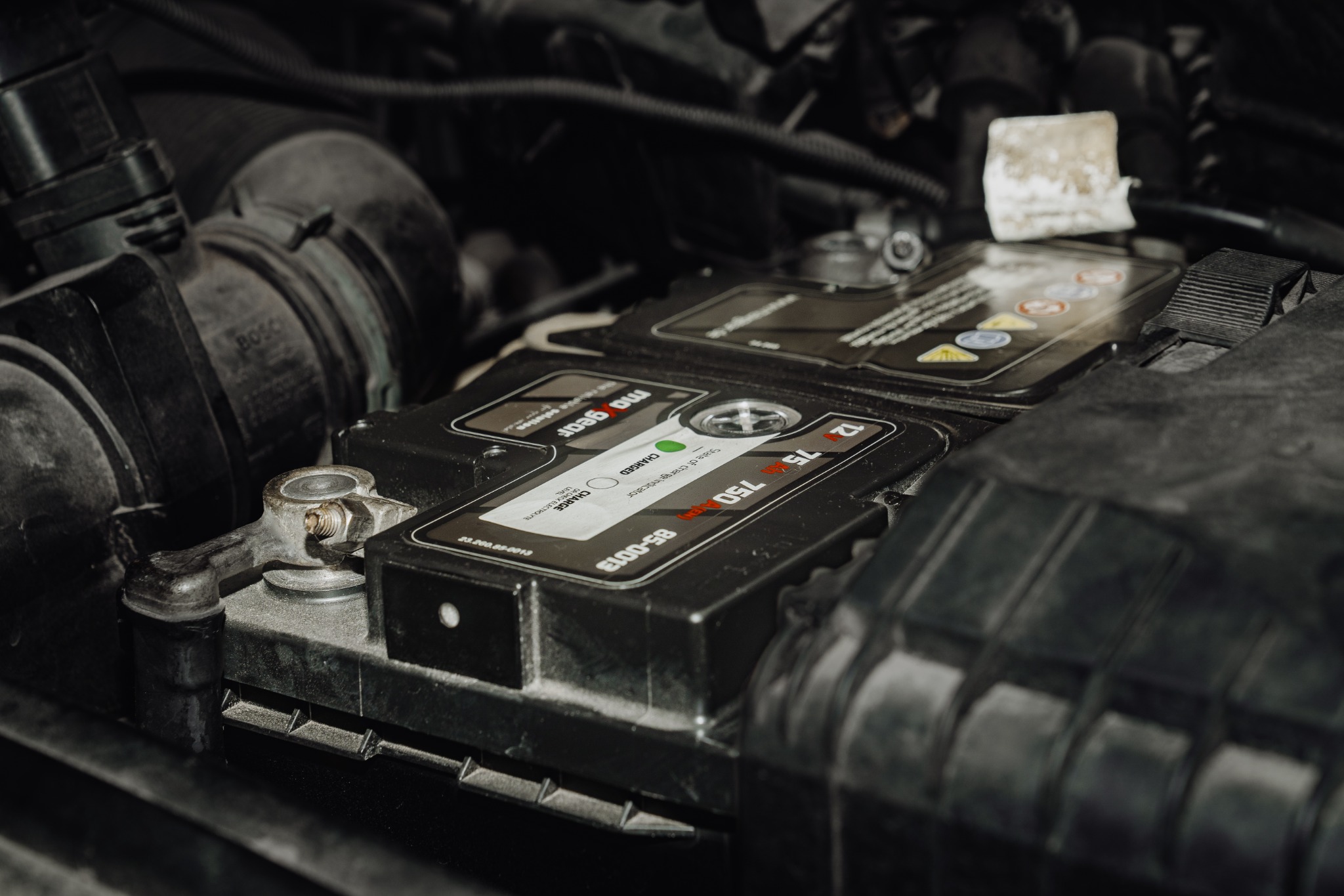 Akumulator samochodowy marki MoGear 12V 75Ah 750A w komorze silnika, widoczne klemny i wskaźnik stanu naładowania.