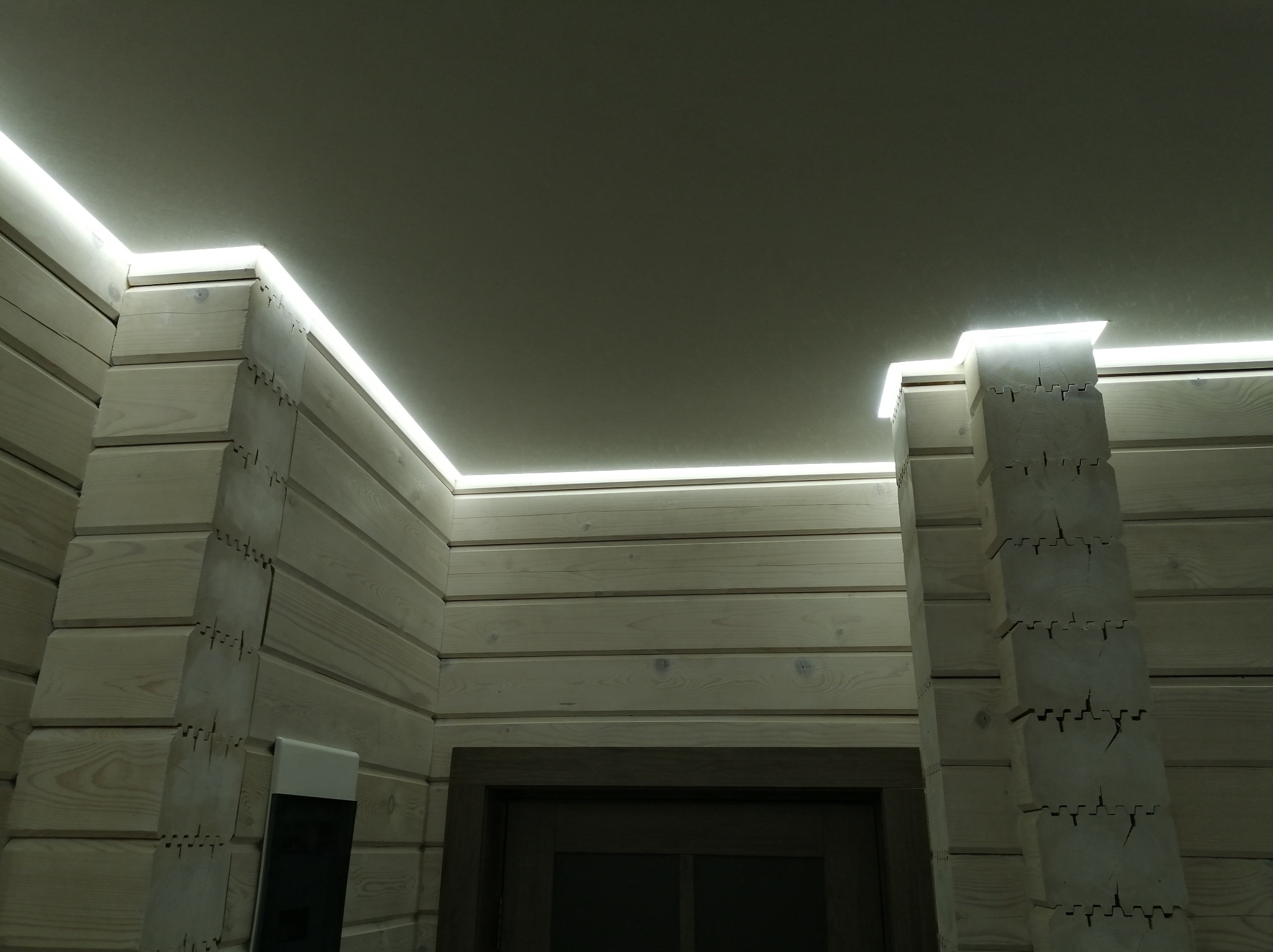 Drewniane wnętrze z podświetlanym sufitem, listwy LED wzdłuż krawędzi, widok z dołu, jasne drewno, nowoczesny design, oświetlenie dekoracyjne.