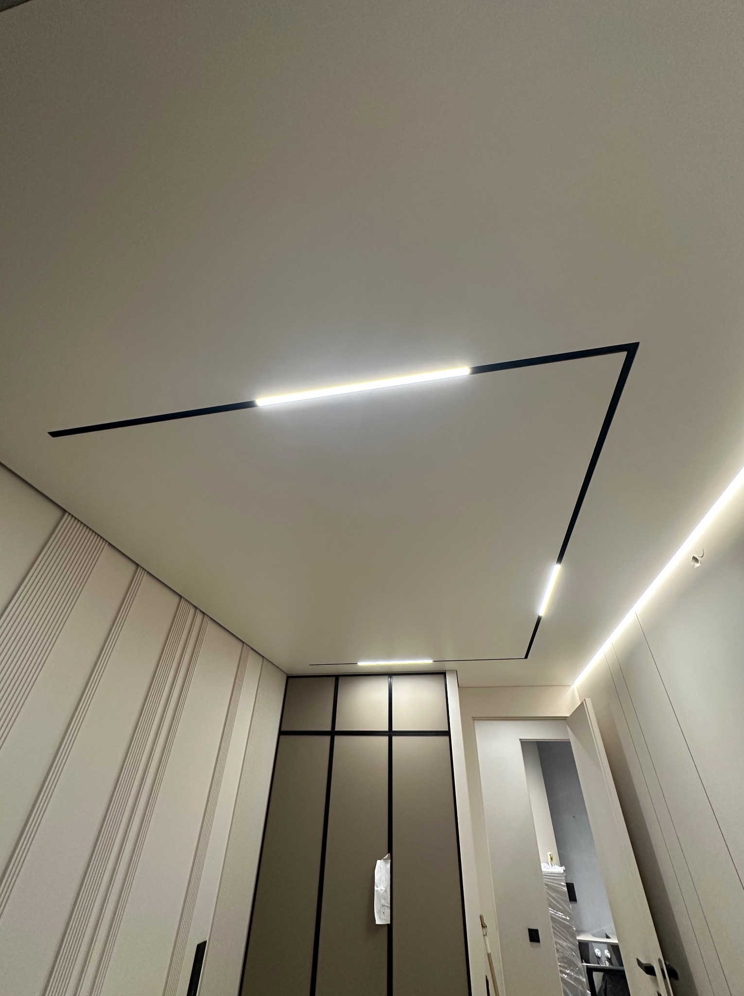 Nowoczesny sufit z liniowym oświetleniem LED w kształcie zygzaka, minimalistyczny design, jasne wnętrze, widok od dołu, eleganckie wykończenie.