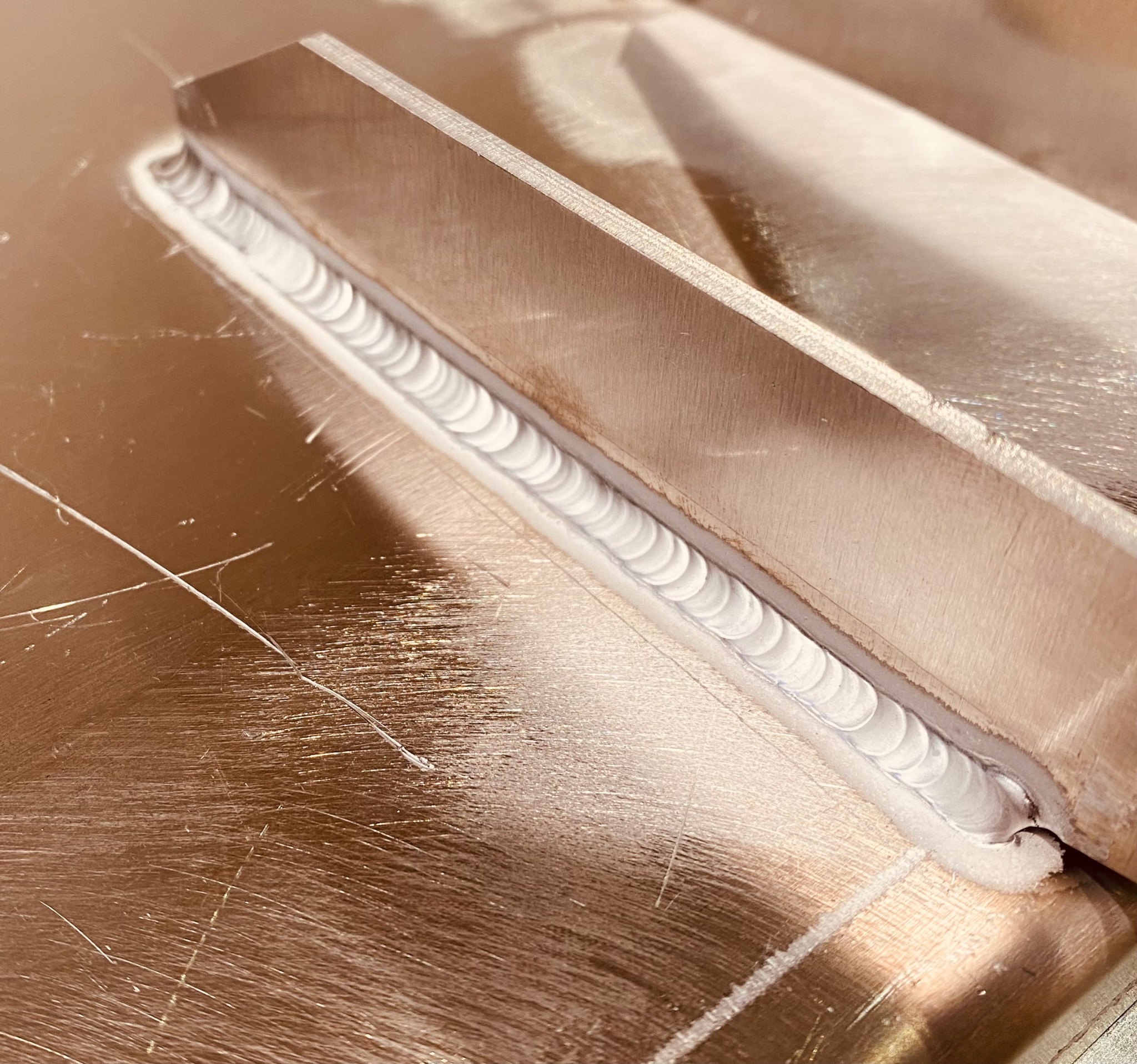 Detal spoiny na metalowej powierzchni, widoczne ślady po procesie obróbki, w tle metalowy element.