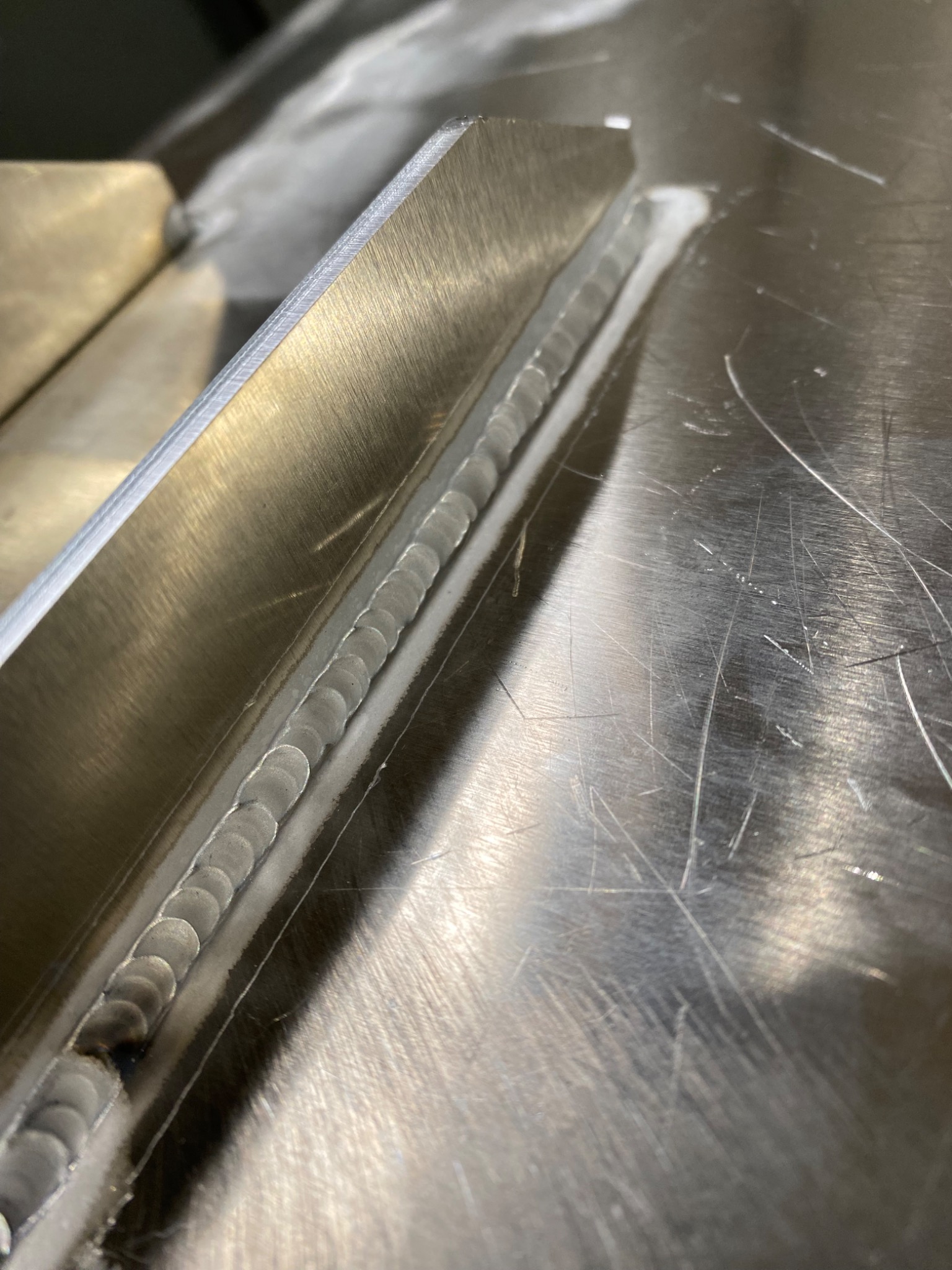 Spoina na metalowej powierzchni, widoczne drobne rysy i ślady obróbki, spaw wykonany metodą punktową.