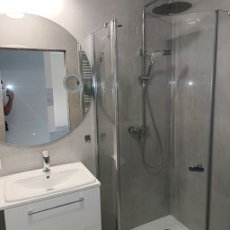 MAZUR BUD Oleksandr Mazur - Nowoczesna łazienka w odcieniach szarości z kabiną prysznicową typu walk-in, okrągłym lustrem z podświetleniem i białą szafką pod umywalką z chromowanymi uchwytami, widoczne odbicie osoby robiącej...