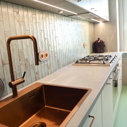 ESEN STUDIO - Nowoczesna kuchnia z miedzianym zlewem i baterią, jasne szafki z uchwytami w kolorze miedzi, płytki w stylu retro i oświetlenie LED pod szafkami.