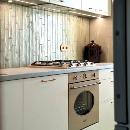ESEN STUDIO - Jasna kuchnia z płytkami w stylu retro, miedziane uchwyty i piekarnik SMEG. Uwagę przykuwa ceramiczny garnek na blacie i nietypowe gniazdko.