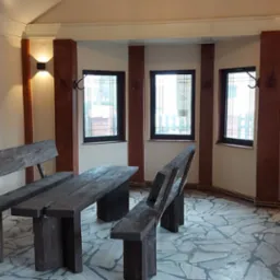 Rustykalna jadalnia z drewnianym stołem i ławkami, kamienną posadzką, ceglanymi filarami i oświetleniem ściennym.