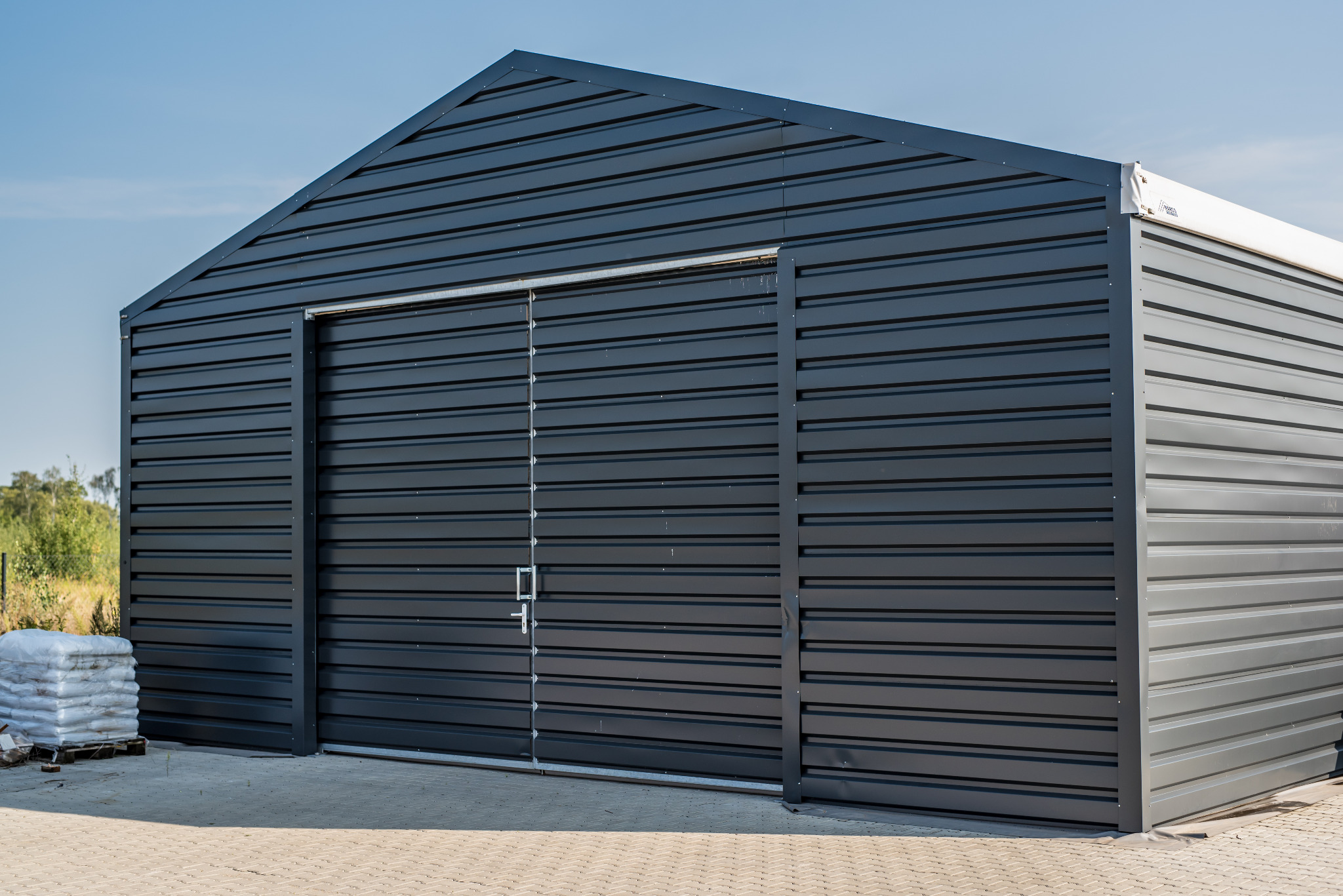 Gotowa, czarna hala z przesuwnymi drzwiami w Głuchowie, z boku widoczny paleta z workami.