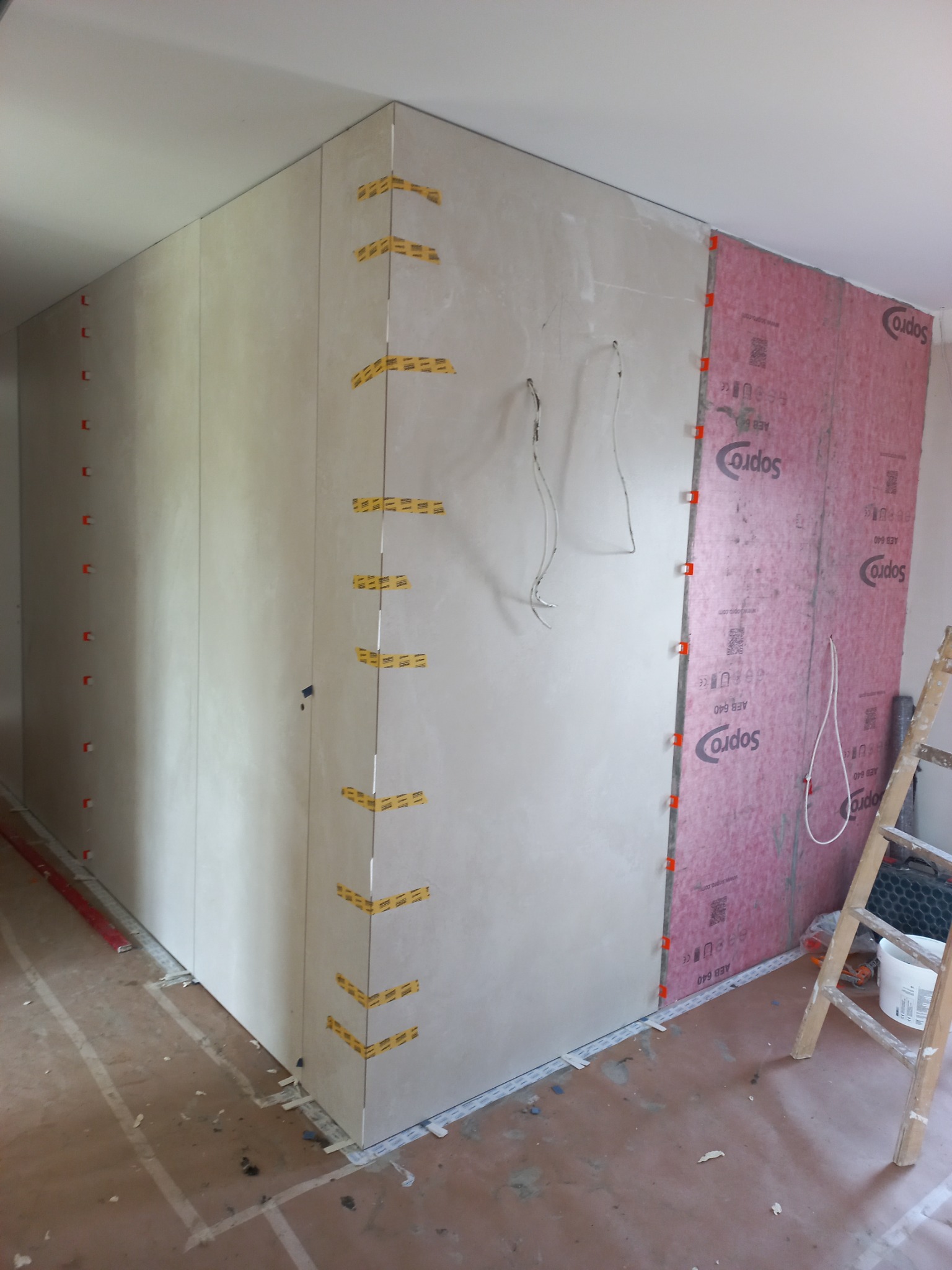 Montaż płytek w narożniku ścian w Gorzowie Wielkopolskim, widoczne listwy wyrównujące, taśma klejąca i hydroizolacja Sopro na jednej ze ścian.