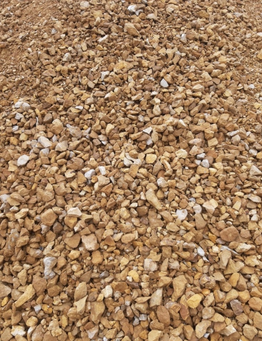 Góra żwiru o brązowo-beżowej barwie, mieszanka drobnych i średnich kamieni, widoczne białe przebarwienia na niektórych fragmentach.