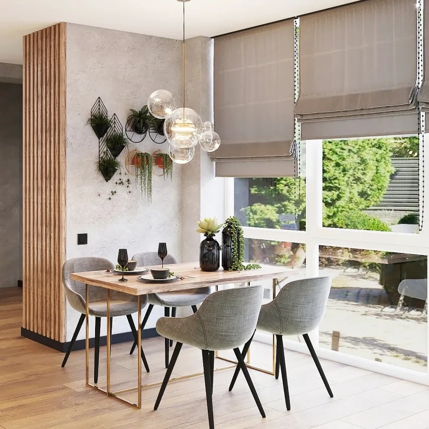 Jadalnia w stylu nowoczesnym: drewniany stół z metalowymi nogami, szare krzesła tapicerowane, lampa wisząca z szklanych kul, dekoracje roślinne na ścianie i w wazonach, rolety rzymskie w oknie...