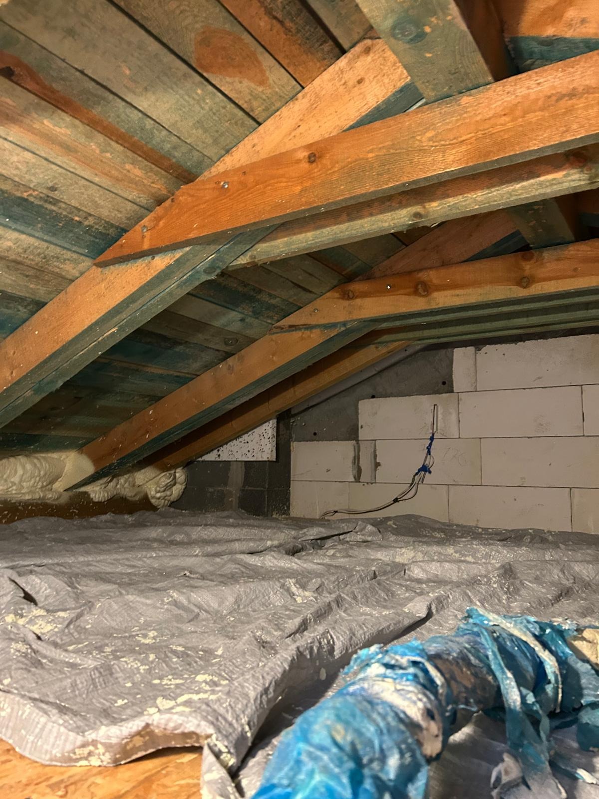 Poddasze z widoczną izolacją pianką PUR w przestrzeni między krokwiami w Gdańsku. Folia ochronna na podłodze, ściany z bloczków.