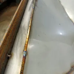 Metalowa konstrukcja z widocznym, precyzyjnym spoiwem po procesie łączenia metali, ukazującym charakterystyczne tęczowe zabarwienie wzdłuż linii spawu.