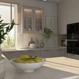 Jasna kuchnia z marmurowym blatem, na którym stoi biała misa z cytrynami i wazon z zieloną rośliną. W tle okno z widokiem na zieleń, zabudowane szafki z przeszklonymi drzwiczkami oraz piekarnik...