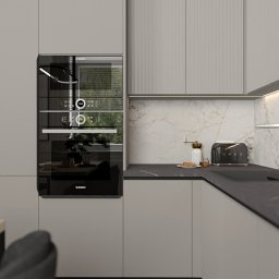 Pracownia Architektury Wnętrz Klaudia Woźniak - Minimalistyczna kuchnia w odcieniach szarości z zabudową kuchenną, piekarnikiem Bosch, tosterem Smeg na blacie z marmurowym wzorem i oświetleniem LED pod szafkami.