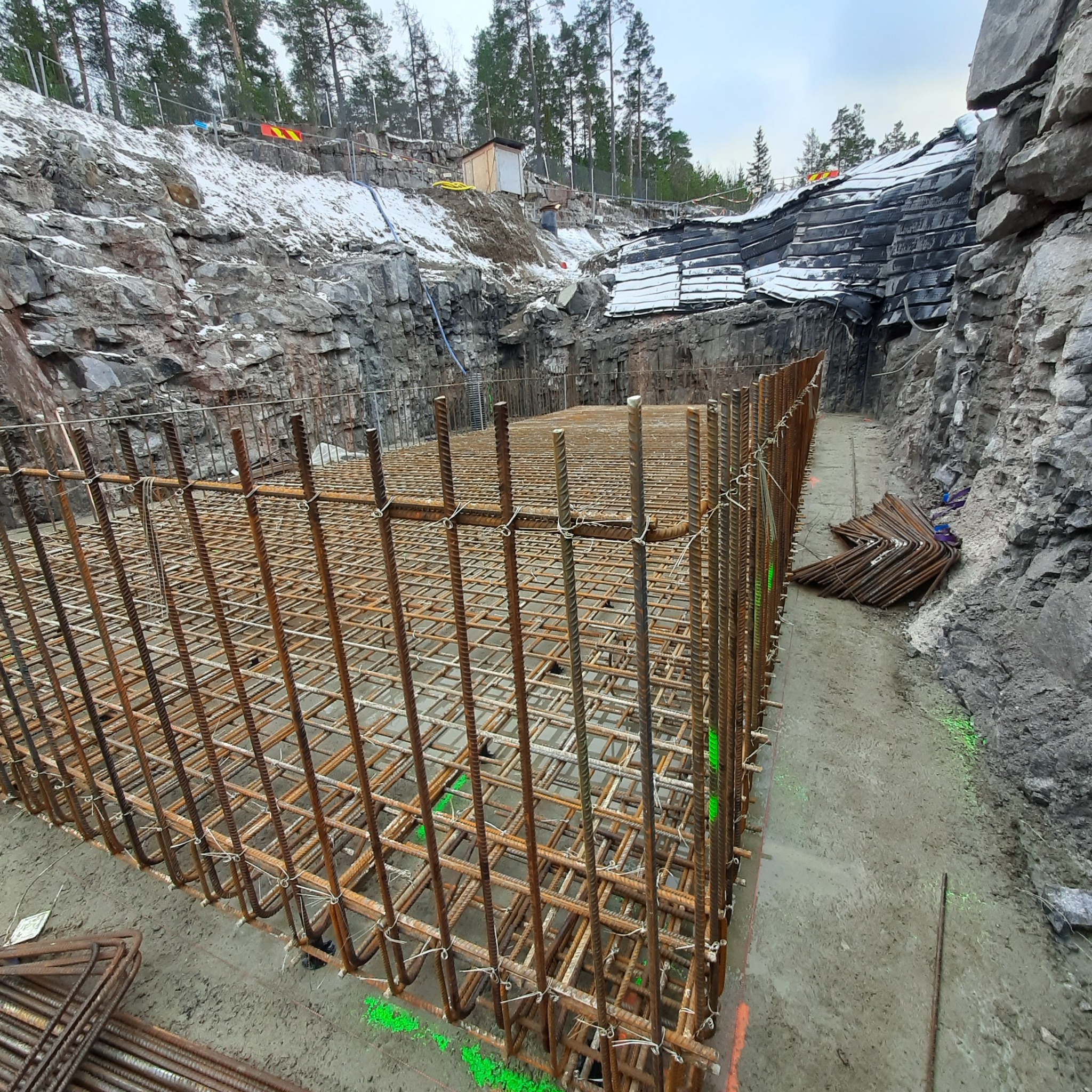 Siatka zbrojeniowa ułożona w wykopie fundamentowym, otoczona skalistym terenem i resztkami śniegu.