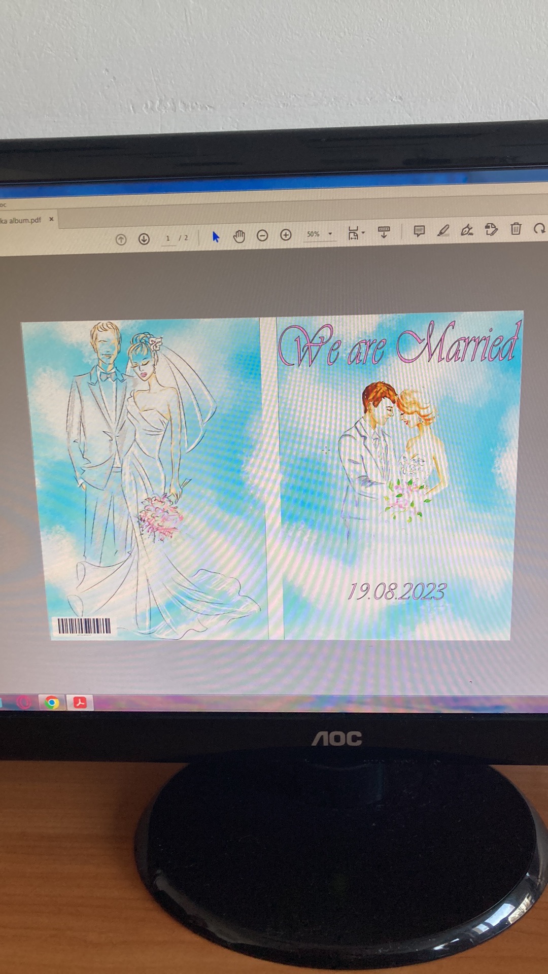 Projekt okładki albumu ślubnego z ilustracją pary młodej na tle nieba, widoczny na ekranie monitora.