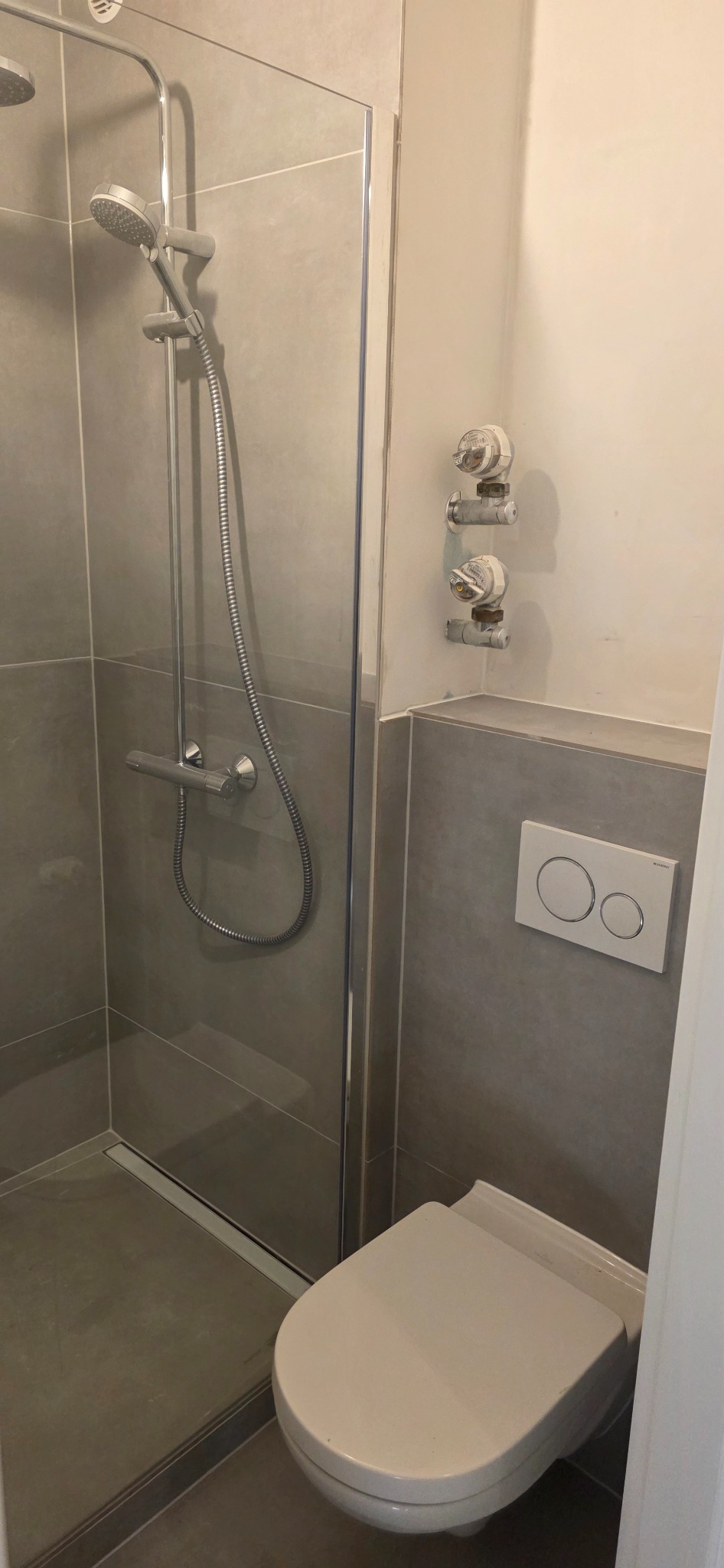 Wykończona łazienka z kabiną prysznicową i podwieszaną toaletą w szarych tonacjach, Dąbrowa Górnicza. Minimalistyczny design, nowoczesne rozwiązania.