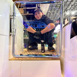 K&L profesjonalne czyszczenie - Mężczyzna w czapce NY i rękawicach, kuca w wejściu do kabiny jachtu, obok butelka środka czyszczącego, widoczna podświetlana nazwa 'GALEON'.