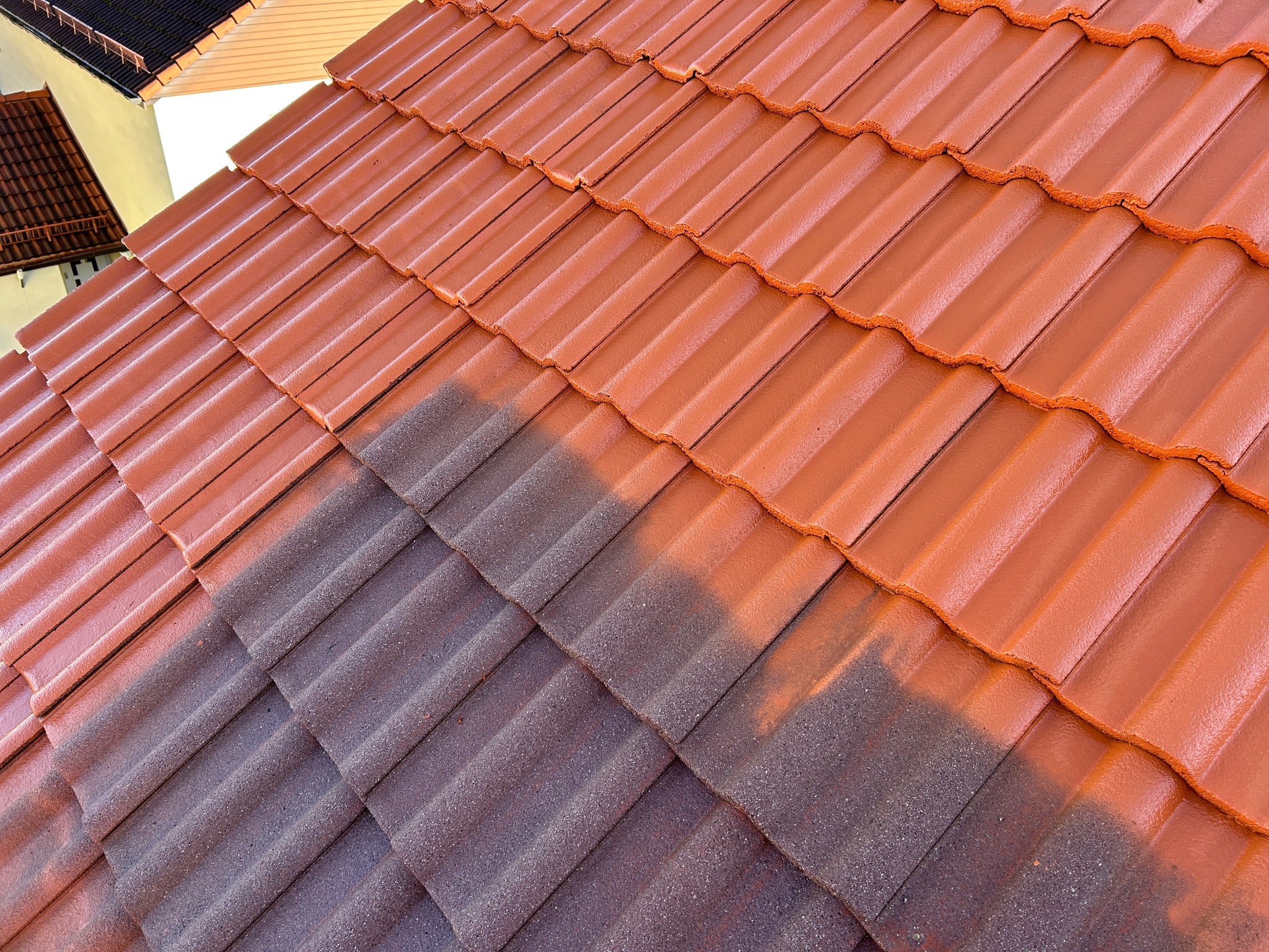 Częściowo odnowiony dach z czerwonej dachówki, widoczna różnica w kolorze między starą a nową warstwą.