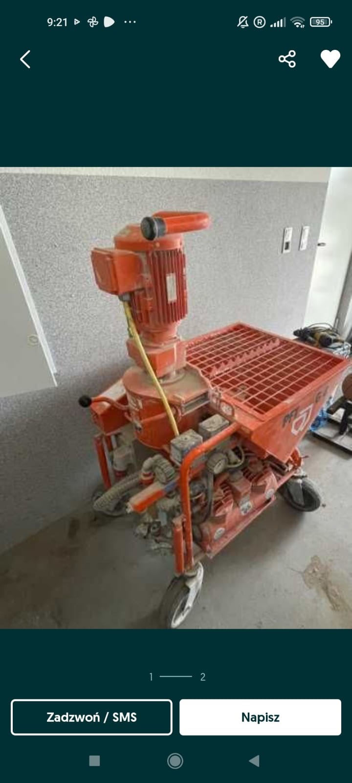 Pomarańczowa, używana maszyna do tynkowania PFT G4 z widocznymi śladami zaprawy i kurzu, stojąca na szarej podłodze w pomieszczeniu w trakcie prac wykończeniowych.