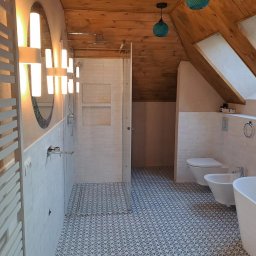 Yolo Bartosz Antonik - Nowoczesna łazienka na poddaszu z drewnianym sufitem, kabiną prysznicową typu walk-in, umywalką, bidetem i toaletą, oświetlona designerskimi lampami w kształcie kuli.