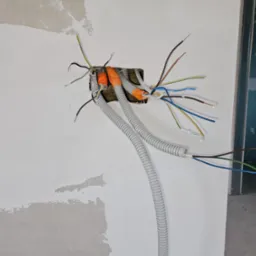 Instalacja elektryczna w trakcie montażu w ścianie w Czańcu, widoczne kable w peszlach i puszka instalacyjna.