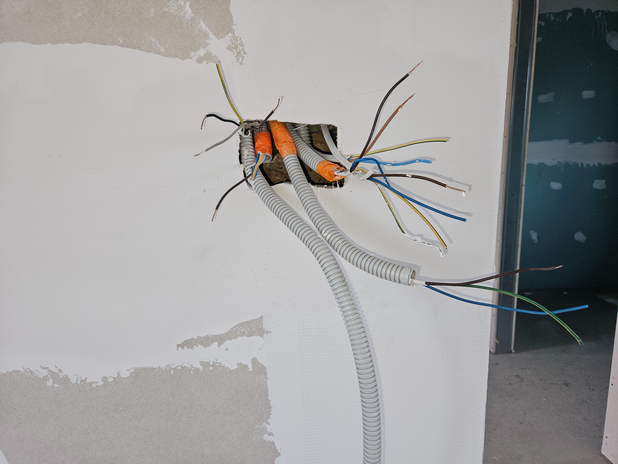 Instalacja elektryczna w trakcie montażu w ścianie w Czańcu, widoczne kable w peszlach i puszka instalacyjna.