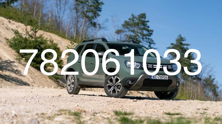 Zielony samochód terenowy Dacia Duster zaparkowany na piaszczystej drodze z widokiem na las i błękitne niebo.