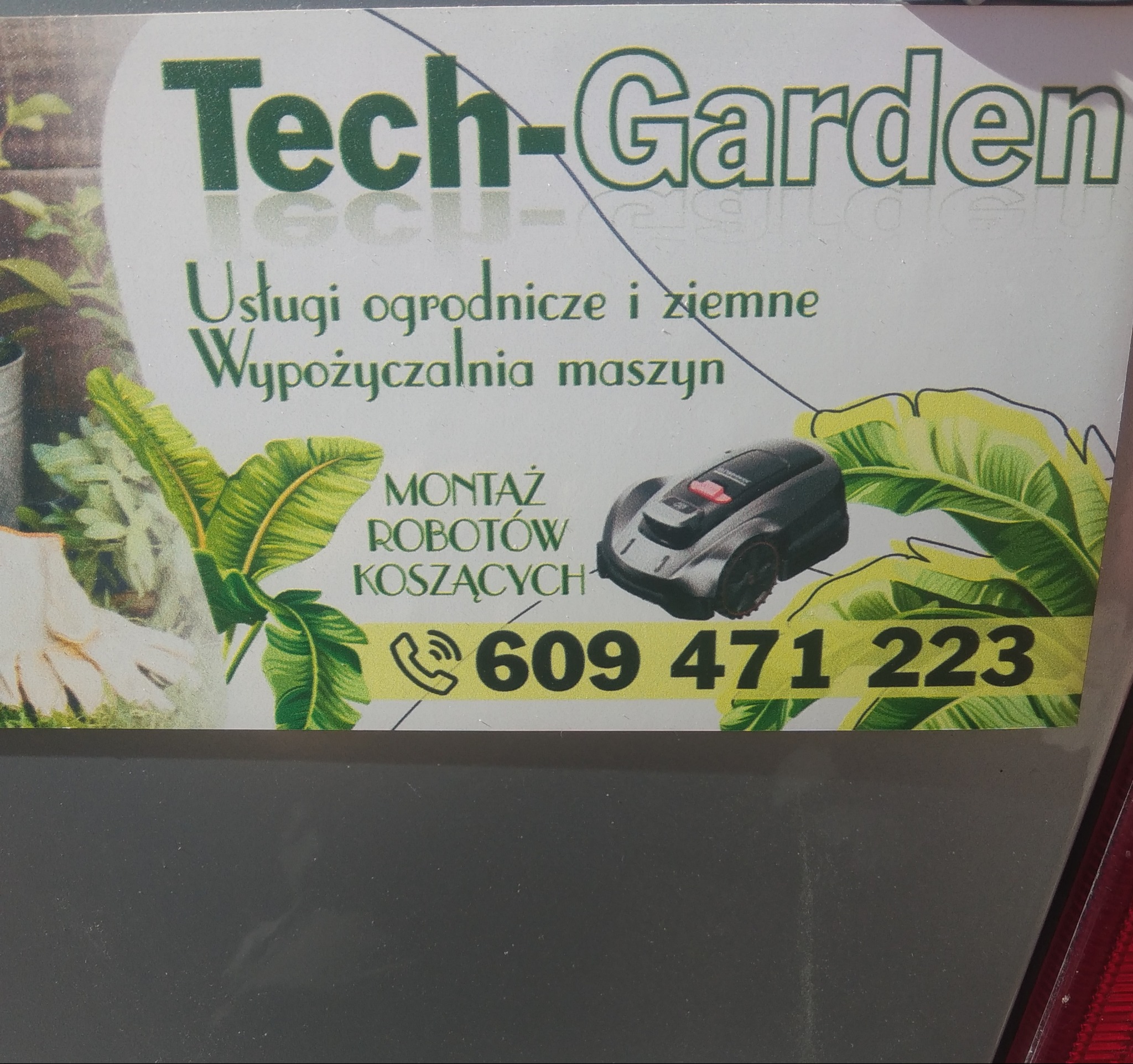 Wizytówka firmy Tech-Garden z ofertą usług ogrodniczych, ziemnych i wypożyczalnią maszyn. Na grafice robot koszący i numer telefonu.