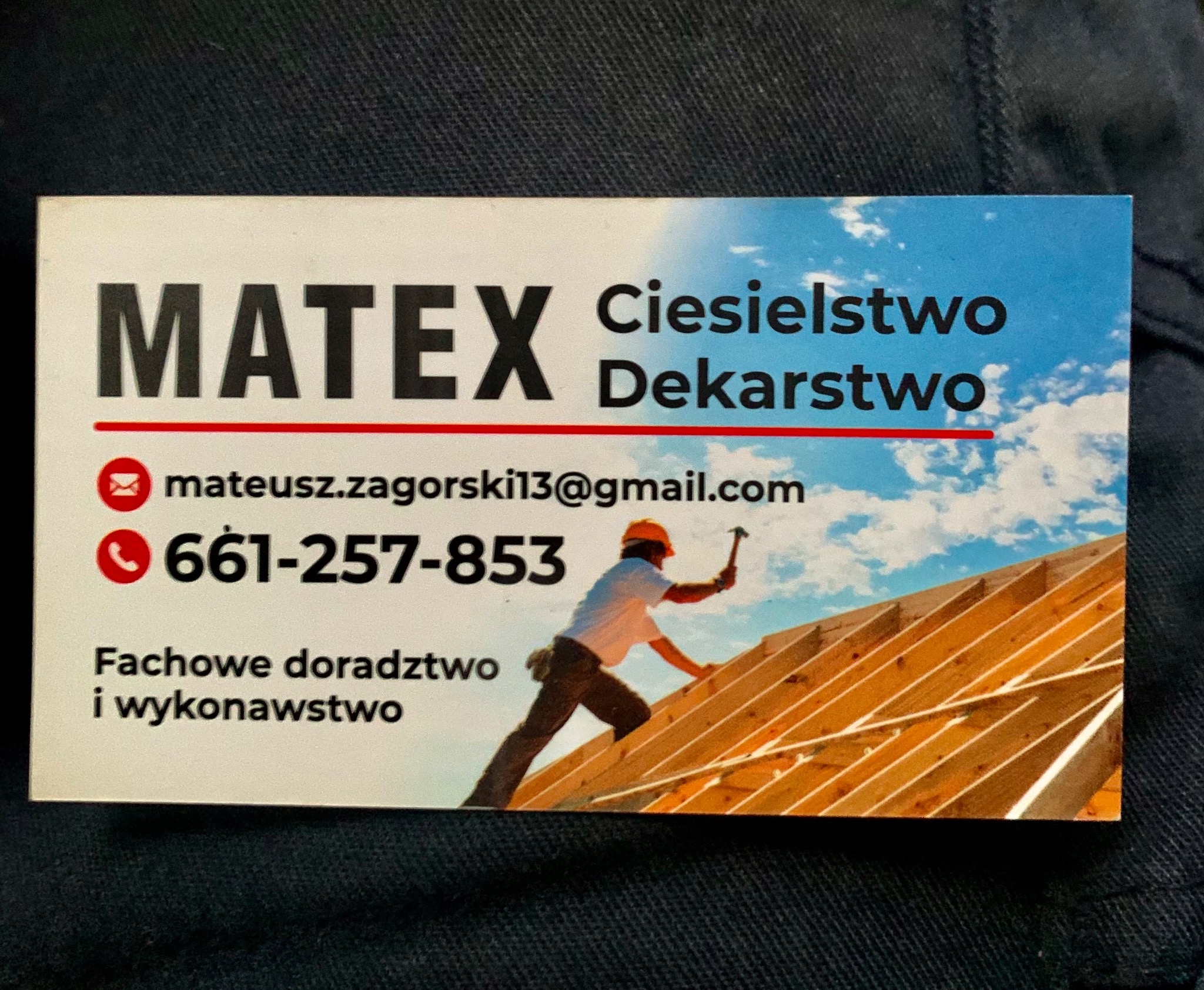 Wizytówka firmy MATEX Ciesielstwo Dekarstwo z adresem email mateusz.zagorski13@gmail.com i numerem telefonu 661-257-853, przedstawiająca dekarza w kasku pracującego na drewnianej konstrukcji dachu...