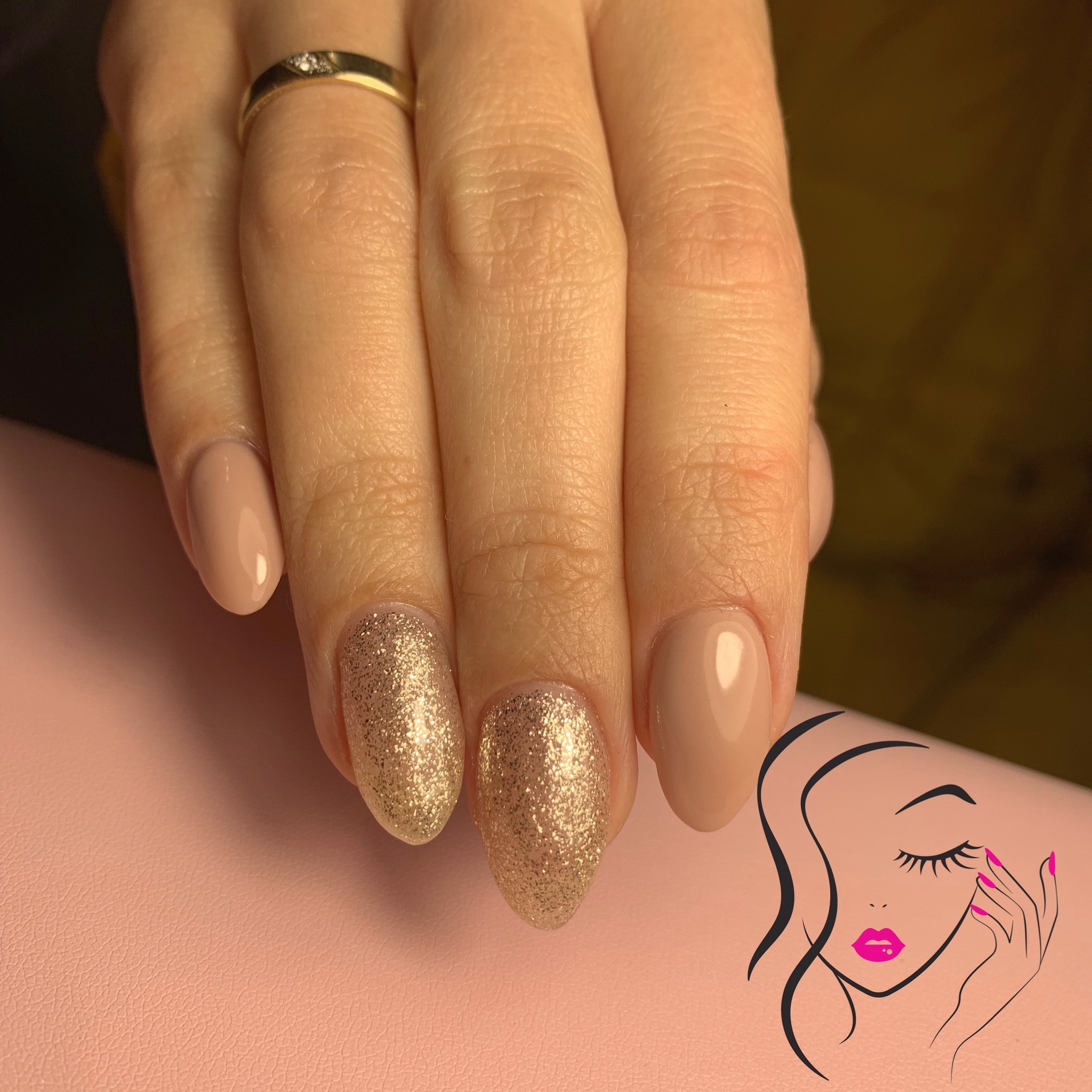 Dłoń z manicure hybrydowym: dwa paznokcie w kolorze nude, dwa pokryte złotym brokatem, na serdecznym palcu złoty pierścionek. W tle różowe podłoże i grafika z wizerunkiem kobiety.