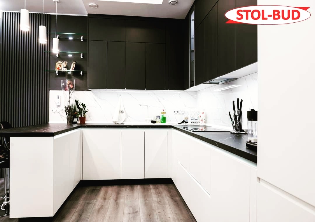 Nowoczesna kuchnia w kształcie litery U z białymi frontami szafek dolnych i czarnymi szafkami górnymi, czarny blat i marmurowy backsplash, oświetlenie punktowe i dekoracyjne akcenty na półkach...