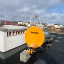 Antena satelitarna Televes i antena naziemna zamontowane na dachu w Kielnie, widok na miasto w tle.