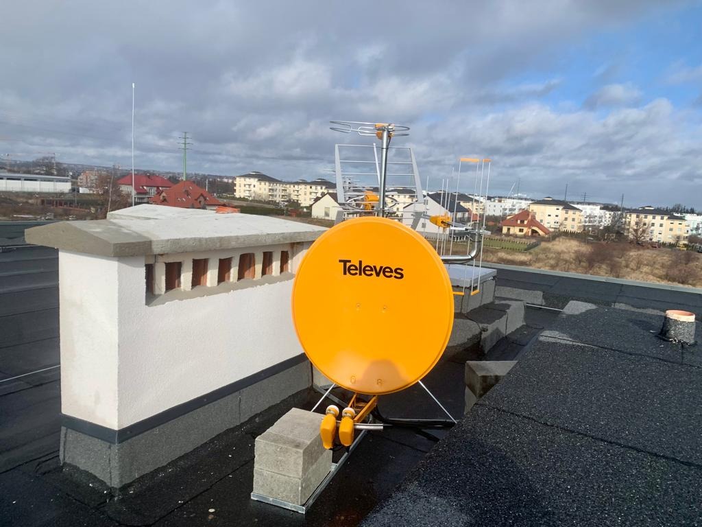Antena satelitarna Televes i antena naziemna zamontowane na dachu w Kielnie, widok na miasto w tle.