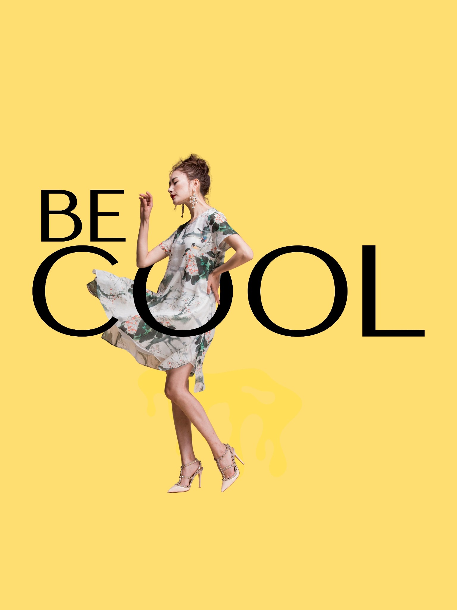 Kobieta w kwiecistej sukience i szpilkach pozuje na żółtym tle z napisem 'BE COOL'.
