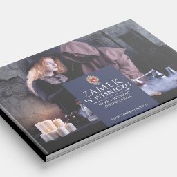 PERFEKTDRUK Joanna Zięba - Katalog reklamowy Zamku w Wiśniczu z wizerunkiem kobiety w stroju wiedźmy i mnicha na okładce, obok płonące świece i alchemiczne naczynia z dymem.