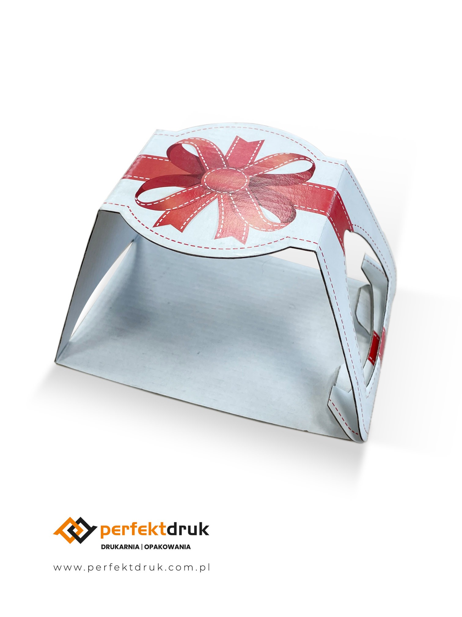 Białe, kartonowe pudełko z nadrukowaną czerwoną kokardą, z widocznymi liniami bigowania i wycięciami, prezentowane na białym tle.