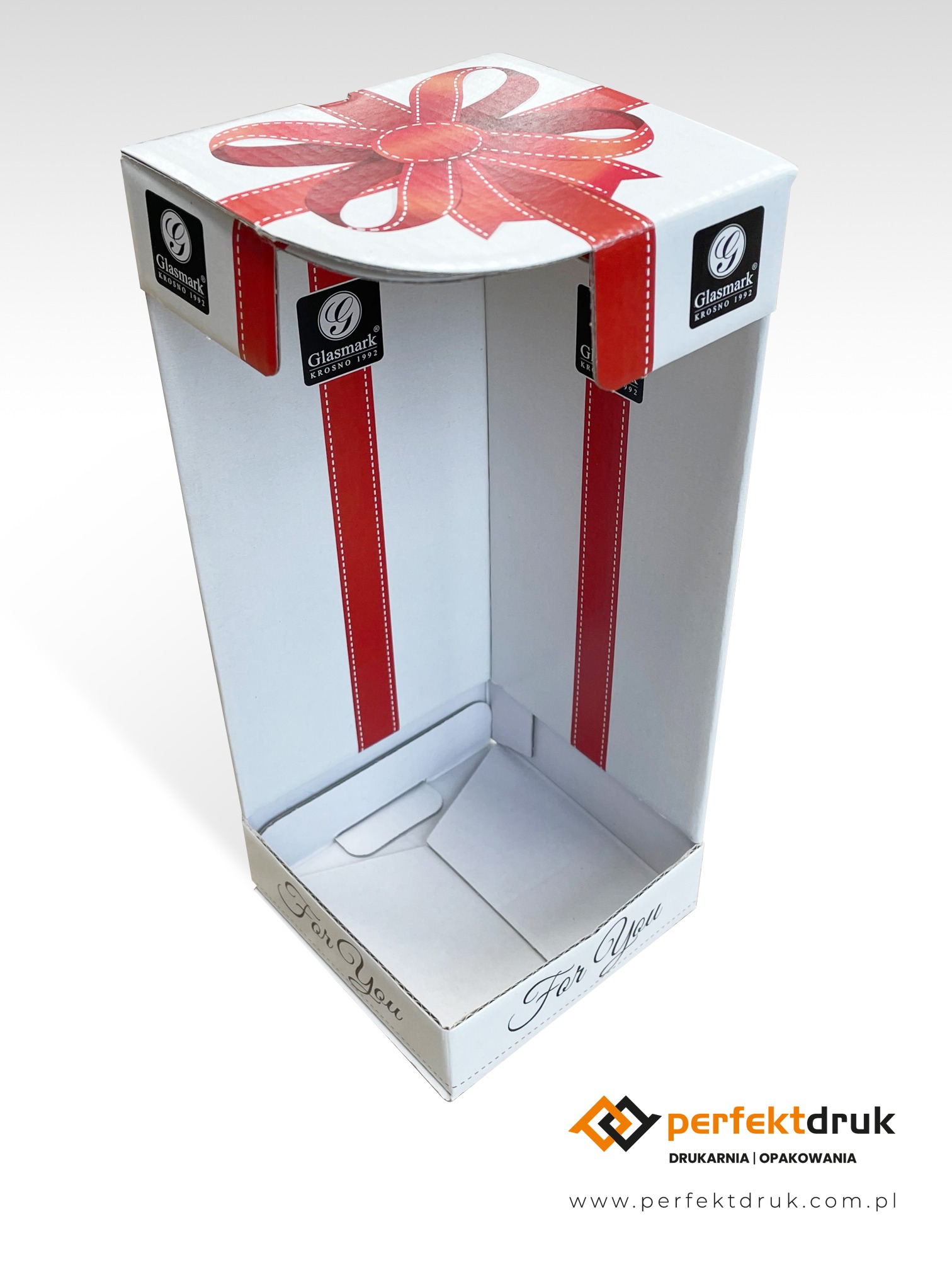 Biały, kartonowy display POS z nadrukiem czerwonej wstążki i logotypem Glasmark, przeznaczony do ekspozycji produktów w punkcie sprzedaży.