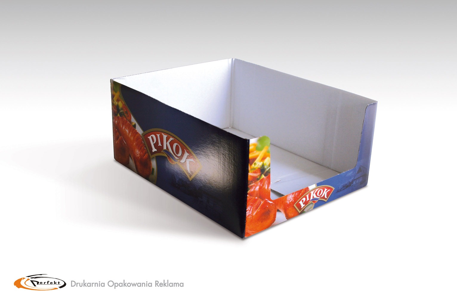 Puste tekturowe pudełko z nadrukowanym motywem kiełbas 'Pikok', ustawione na białym tle i oświetlone z góry, z widocznym logotypem drukarni w lewym dolnym rogu.