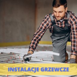 P.H.U Mateusz Majchrzak Hydro-Mat - Instalator w kombinezonie i rękawicach układa białe rurki na siatce ogrzewania podłogowego w surowym wnętrzu.