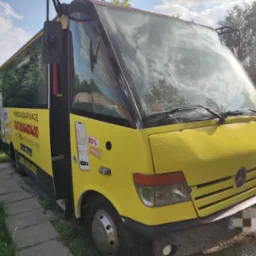 Żółty bus Mercedes z reklamą aplikacji mobilnej do zamawiania taksówek, zaparkowany na zewnątrz, widok z przodu i boku.