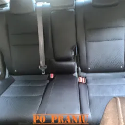 Wnętrze samochodu z widoczną tylną kanapą po czyszczeniu, ukazującą odświeżoną tapicerkę z wyraźnym wzorem i pasami bezpieczeństwa.